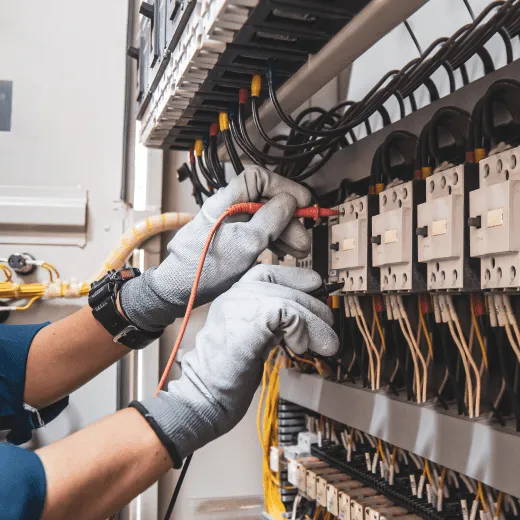 Un électricien travaille sur un équipement électrique avec des gants.